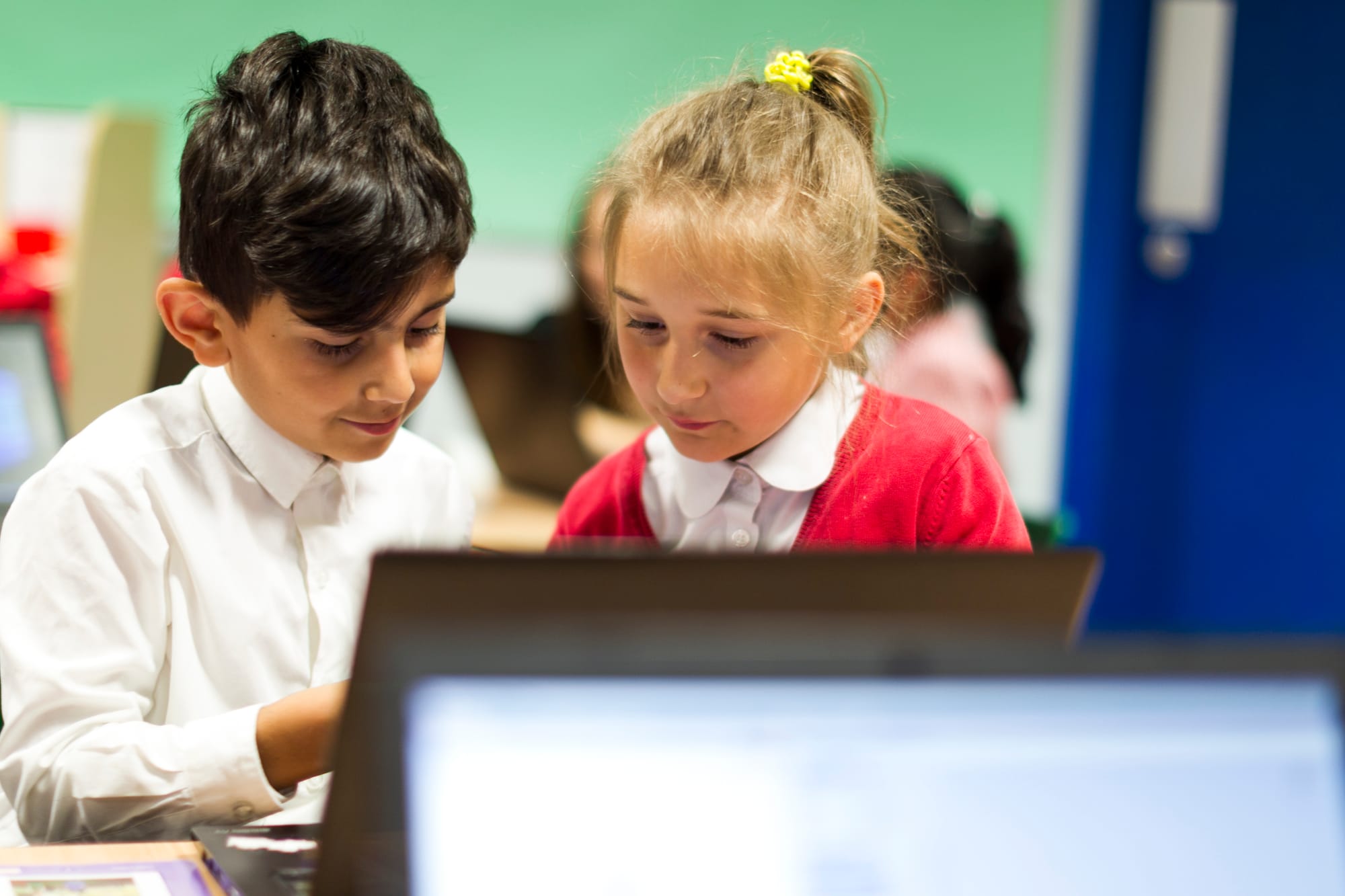 Two primary school students in their computer science lesson, working on a laptop together. 